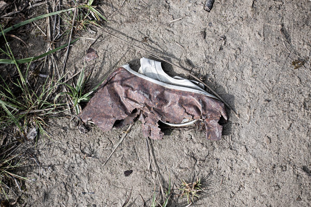 Canette déchirée — sculpture abandonnée dans la terre